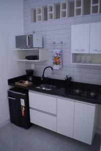 uma cozinha com armários brancos e um balcão preto em Flamengo Home no Rio de Janeiro