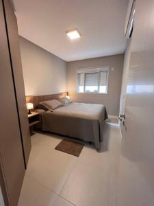 um quarto com uma cama, uma janela e uma porta em Lindo apt Garden Cannes Club em Florianópolis