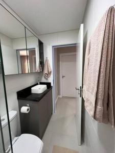 uma casa de banho com um WC, um lavatório e um espelho. em Lindo apt Garden Cannes Club em Florianópolis
