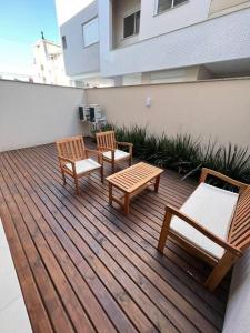 um deque com duas cadeiras e dois bancos num edifício em Lindo apt Garden Cannes Club em Florianópolis