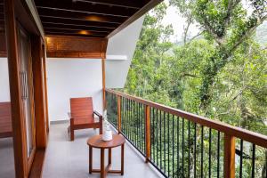 a room with a balcony with a chair and a table at Lush Acres in Thekkady