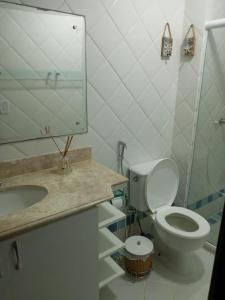 een badkamer met een toilet, een wastafel en een spiegel bij Duplex em Praia do Forte a 50m da vila in Mata de Sao Joao