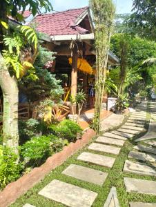 a garden with a walkway in front of a house at Junia Guesthouse Bukit Lawang in Bukit Lawang