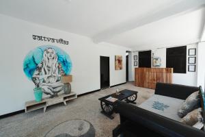 a living room with a couch and a painting on the wall at Sattva Yoga retreat villas in Canggu