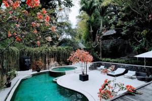 a swimming pool in a garden with trees and flowers at Sattva Yoga retreat villas in Canggu
