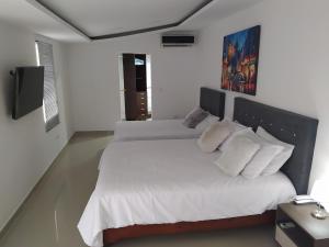 a white bedroom with two beds with white pillows at Habitación Amoblada Tipo Hotel in Tuluá
