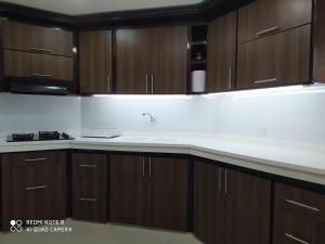 cocina con armarios de madera y encimera blanca en Habitación Amoblada Tipo Hotel en Tuluá