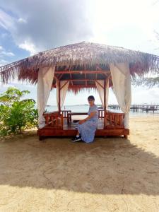 a woman sitting on a bench on the beach at Hello Bintan in Kangkakawal