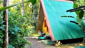 uma pequena casa com um telhado verde numa floresta em Chalets Silencio del Bosque em Fortuna