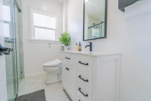 uma casa de banho branca com um WC e um espelho. em White Heaven House em Compton
