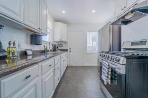 uma cozinha com armários brancos e um forno com placa de fogão em White Heaven House em Compton