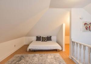 a white bedroom with a bed in a attic at Charming 3BR Century Home in Downtown Barrie in Barrie
