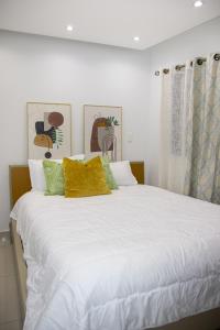 a large bed with white sheets and yellow pillows at Casa de Nini in Santo Domingo