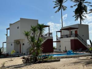 una casa en la playa con una piscina y palmeras en Chansi Beachresort en Tha Sala