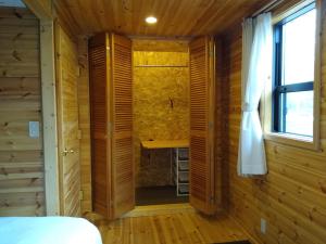 Holzzimmer mit einem Bett und einem Fenster in der Unterkunft Robin's Lodge in Iiyama