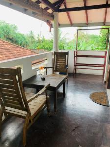 porche con 2 sillas y mesa de madera en Deshan Homestay & Restaurant, en Tangalle