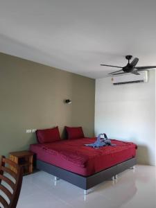 a bedroom with a red bed with a ceiling fan at Spy home in Khao Lak