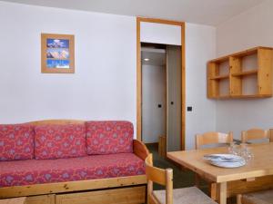 a living room with a red couch and a table at Appartement fonctionnel au cœur des pistes avec balcon et accès piscine - FR-1-181-2786 in La Plagne Tarentaise