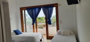 um quarto com 2 camas e uma grande janela em HOSPEDAJE DELFIN AZUL em Puerto Villamil