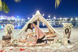um casal a beijar-se debaixo de uma tenda numa praia em Armin Homes Căn hộ 2 Phòng ngủ Vinhomes OCP em Gia Lâm Pho