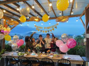a group of people standing around a table with balloons at Đom Đóm House Đà Lạt in Da Lat