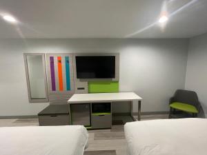 a room with two beds and a desk and a tv at Travel Inn Motel in Anaheim