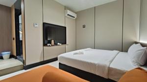 a hotel room with a bed and a flat screen tv at Urban Inn, Serai Wangi in Padang Serai