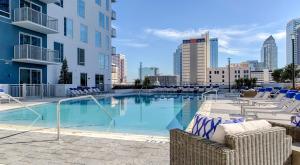 1BR Oasis in Downtown Tampa w Balcony & City Views في تامبا: مسبح كبير مع كراسي ومبنى
