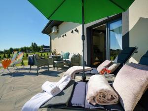 a patio with chairs and a green umbrella at Beautiful terraced house for 5 people, Mielenko in Mielenko