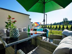um pátio com uma mesa e um guarda-chuva verde em Comfortable terraced house, Mielenko em Mielenko