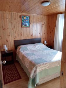 1 dormitorio con 1 cama en una cabaña de madera en Cabaña Don Tito en Buchupureo II, en Buchupureo