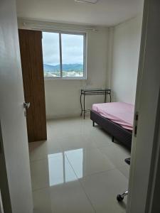 Habitación vacía con cama y ventana en Apartamento 01 en Itapema