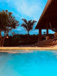una piscina azul con palmeras y un cenador en Casa Castañeto Barichara, en Barichara