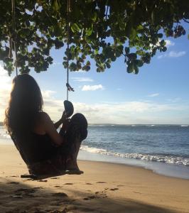 una mujer sentada en un columpio en la playa en BANANAS HOSTEL, en Itacaré