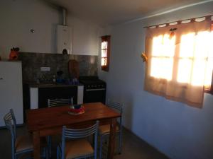 een keuken met een houten tafel en stoelen en een raam bij Cabaña Siquiman in Villa Parque Siquiman