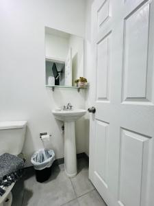 a white bathroom with a sink and a toilet at Casa Ambar in Tijuana