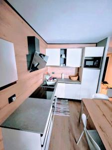 eine Küche mit weißen Schränken und Holzböden in der Unterkunft Maison De Neige - Appartamento Vacanze in Sauze dʼOulx