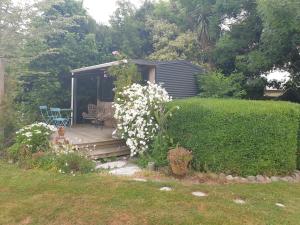 a house with a porch with a deck with flowers at Cabins on Tudor bed & breakfast in Motueka