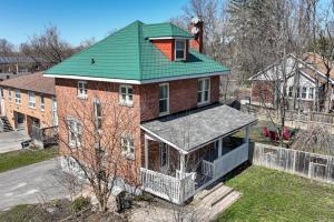 a large brick house with a green roof at Hidden Basement Gem: Cozy Comfort & Outdoor Fun in Barrie