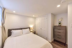 a bedroom with a white bed and a dresser at Hidden Basement Gem: Cozy Comfort & Outdoor Fun in Barrie