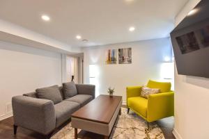 a living room with a couch and a yellow chair at Hidden Basement Gem: Cozy Comfort & Outdoor Fun in Barrie