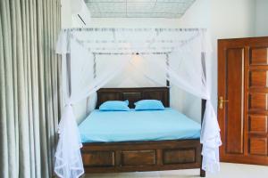 a bedroom with a canopy bed with blue sheets at Amible Guest Home in Mirissa