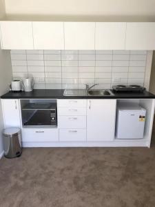 una cucina bianca con lavello e microonde di Otematata Lakeside Apartments Free Wi Fi a Otematata