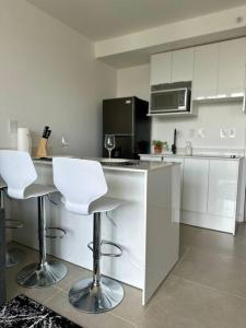 a kitchen with white cabinets and white bar stools at Mango Studio Nunciatura in San José