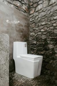 a white toilet in a bathroom with a stone wall at Deduru Cabana Nature Resort in Kurunegala