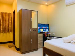 - une chambre avec un lit et une armoire avec une télévision dans l'établissement MCA Hotel Suites, à Bil-isan