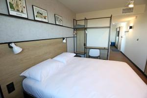 a bedroom with a large white bed and a chair at Ibis Bourgoin Jallieu Medipole in Bourgoin