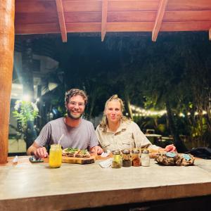 Ein Mann und eine Frau sitzen an einem Tisch mit Essen in der Unterkunft PineApple Surf in Ahangama