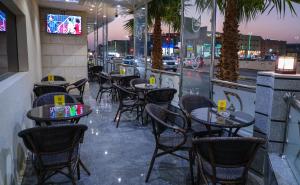 فندق شيرفل الواحة عنيزة Cheerful Al Waha Unayzah Hotel في عنيزة: مطعم به طاولات وكراسي وتلفزيون