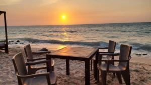 Hugos Place Baru في كارتاهينا دي اندياس: طاولة وكراسي على الشاطئ مع غروب الشمس